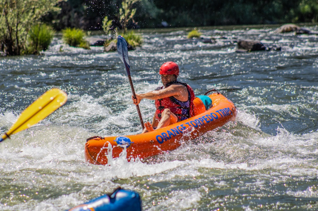 A dad paddling an inflatable kayak through Galice rapid with Orange Torpedo Trips on the Rogue River