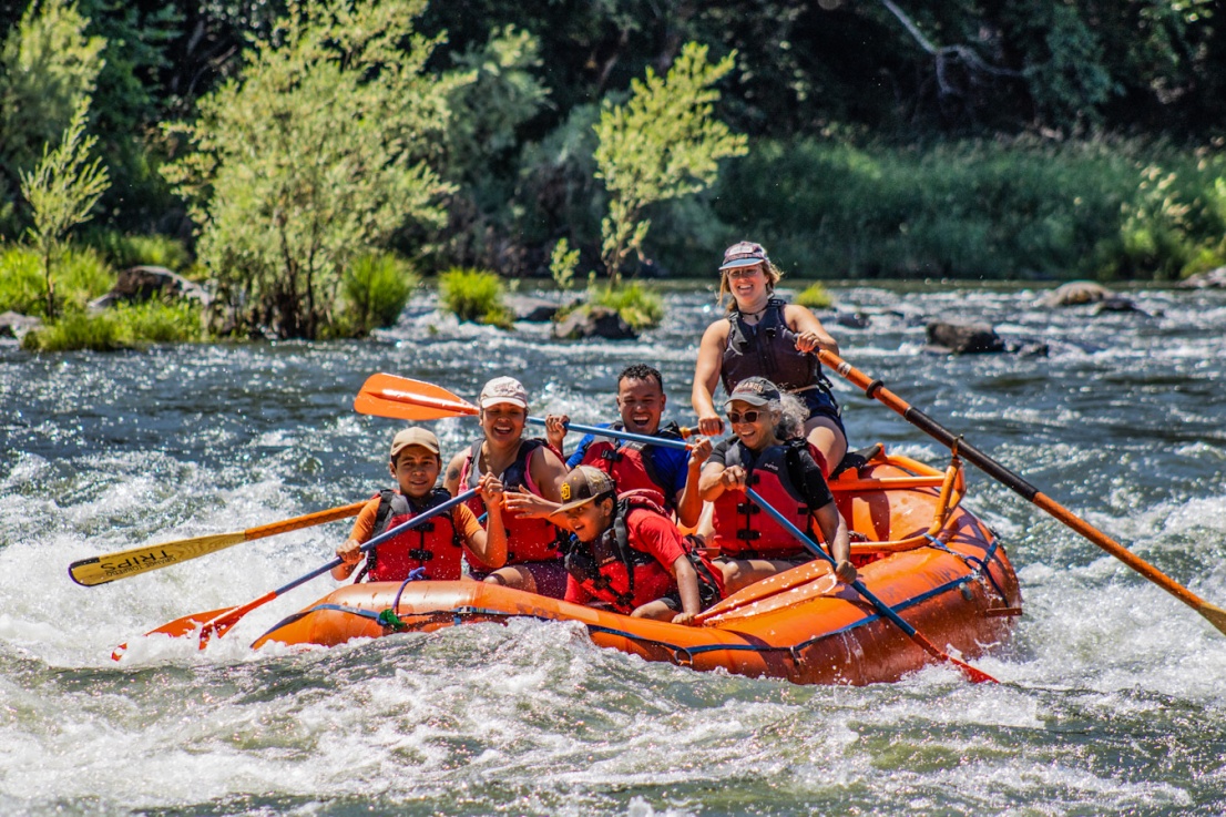 Family in a raft with a female guide from Orange Torpedo Trips on the Rogue River