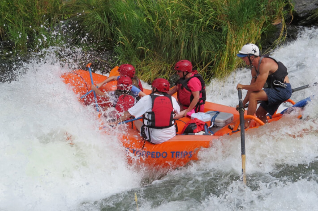 Family in a guided raft going through top wave at Nugget Falls on the Rogue River