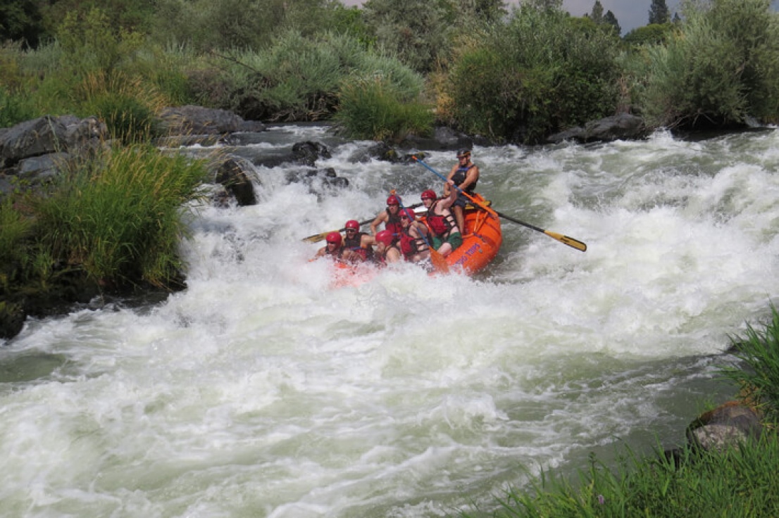 River Guide going into top hole at Nugget Falls with a family in raft.