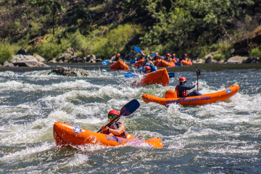 Group of Orange Torpedo Trips inflatable kayaks lined up on the day section of the Rogue River