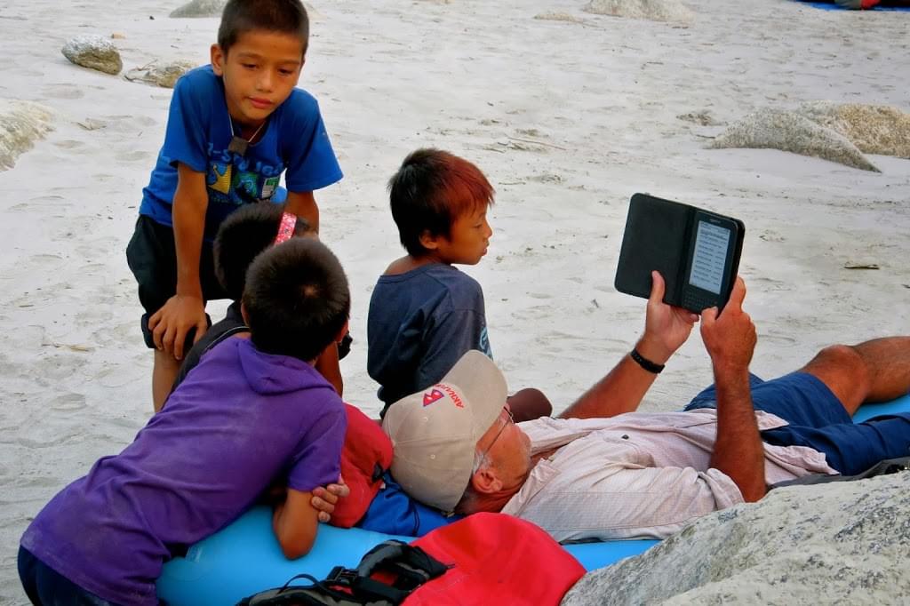 Mike reads his Kindle, not so much to as in the company of some local Nepali boys.